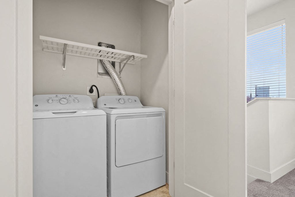 Two white front loading washing machines in a small laundry room.