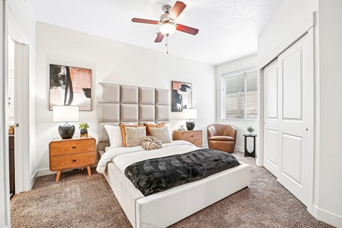A bedroom with a large bed and a ceiling fan.