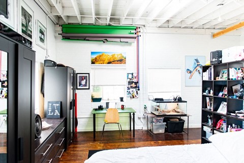 a bedroom with a bed and a desk and a refrigerator