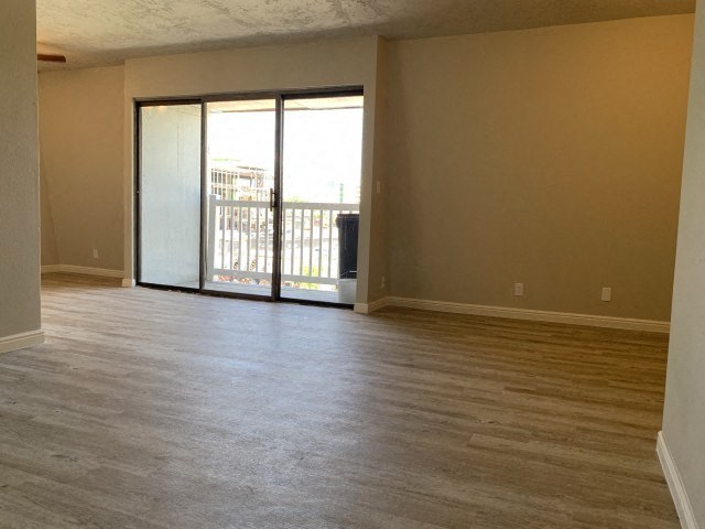 an empty living room with wood floors and a sliding glass door