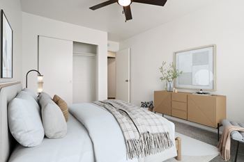 A bedroom with a bed, a dresser, and a ceiling fan.