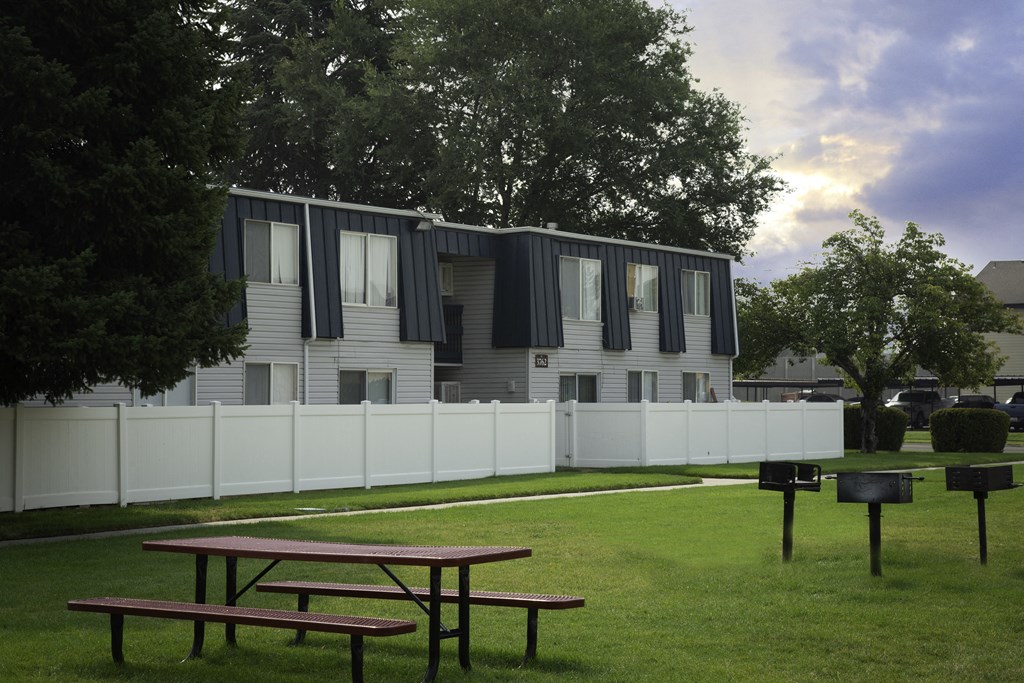 an apartment building with a white fence and two picnic tables