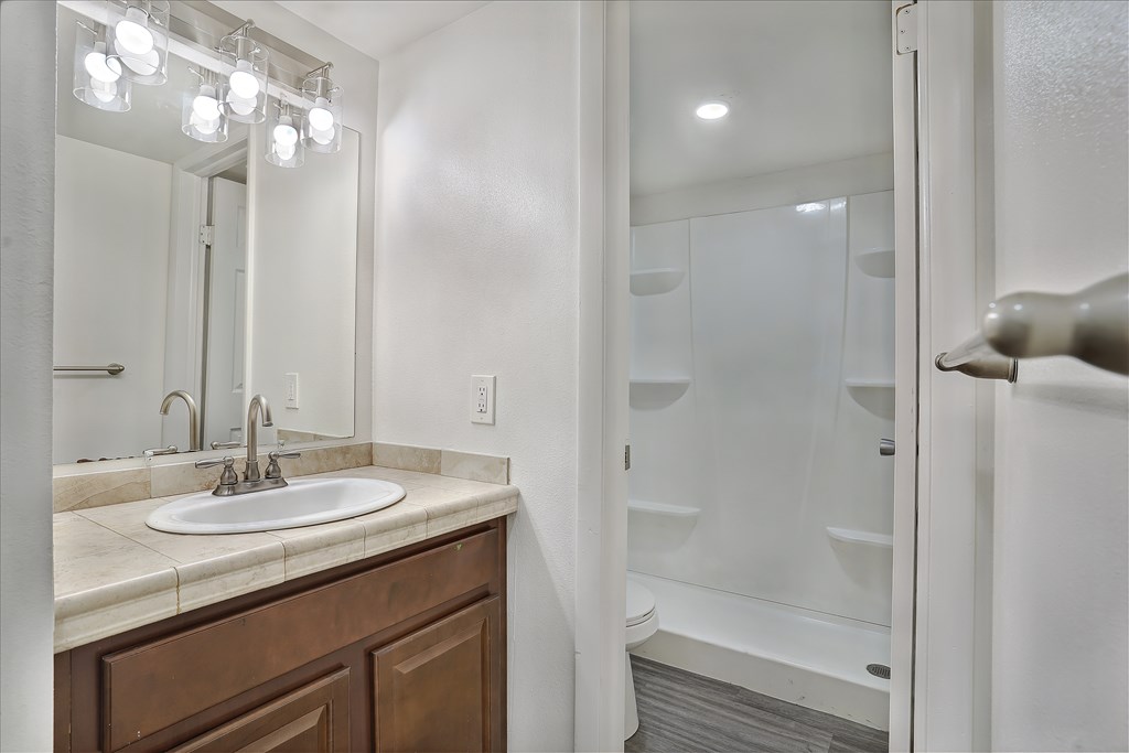 A bathroom with a sink, mirror, and shower.