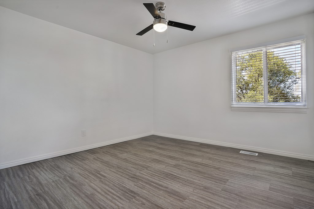 A room with a ceiling fan and a window with blinds.