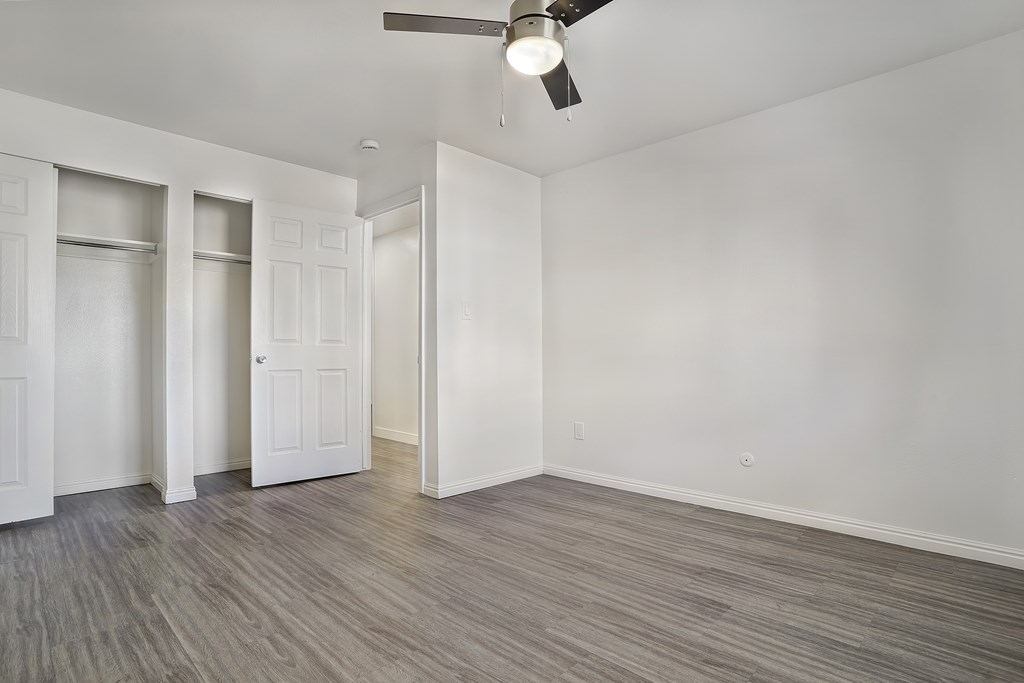 A room with a ceiling fan and wood flooring.