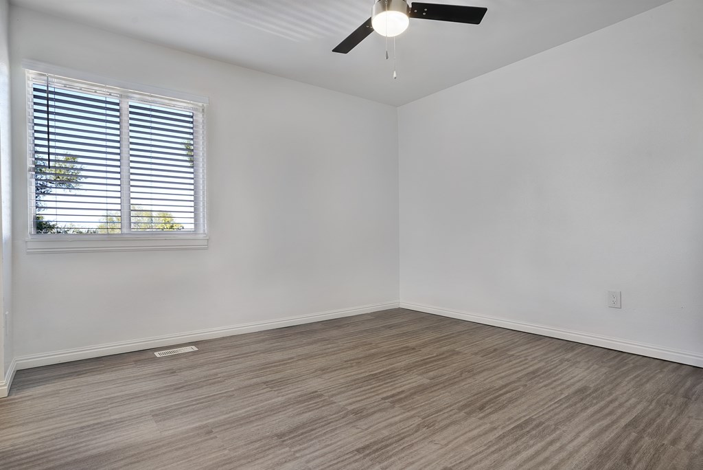 A room with a ceiling fan and a window with blinds.