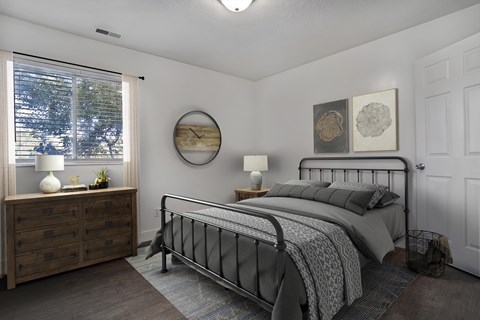 A bedroom with a bed, nightstand, and window.