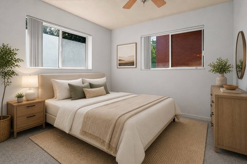 A bedroom with a large bed, a ceiling fan, and a nightstand with a plant on it.