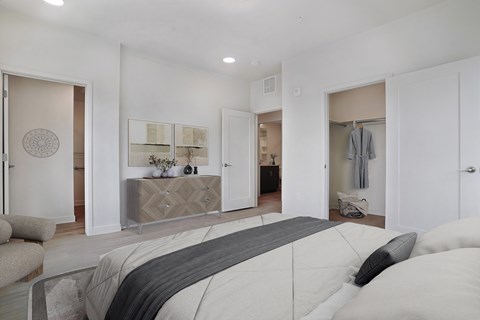 A bedroom with a large bed and a dresser with a mirror above it.