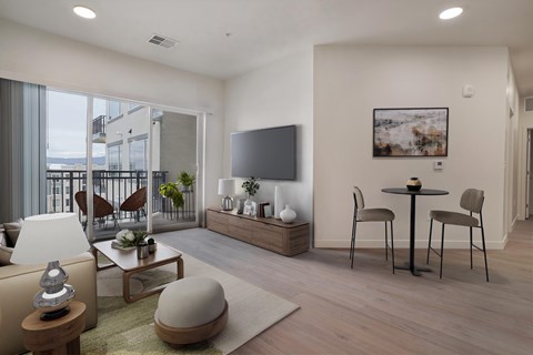 A modern living room with a flat screen TV, a coffee table, and a dining table set up.