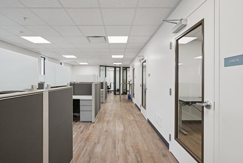 A hallway with cubicles on the left and doors on the right.