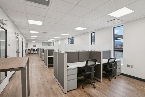 A long hallway with cubicles and chairs on the side.