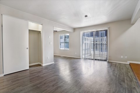 A spacious room with a sliding glass door and hardwood flooring.