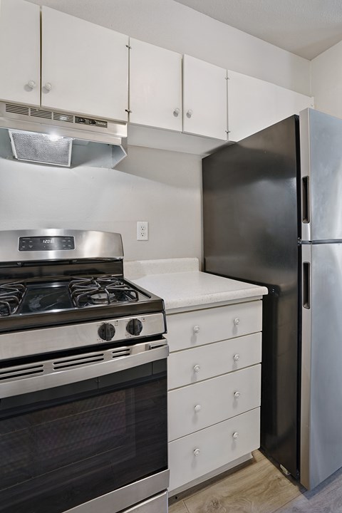 A black refrigerator stands next to a stove in a kitchen.