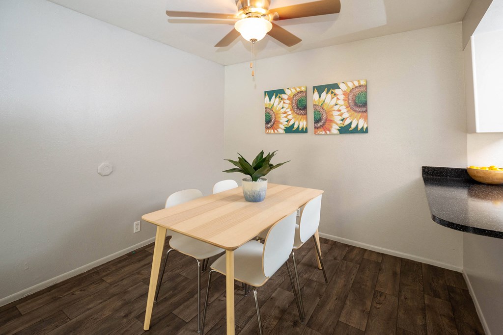 a dining area with a table and chairs and a ceiling fan