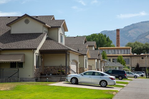 A row of houses with cars parked in front.