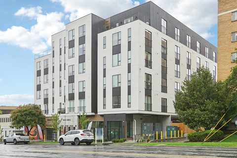 A modern multi-story building with a parking lot in front.
