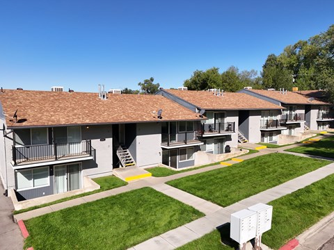 Apartment complex with green grass and trees in the background.