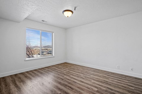 Empty room with a window and wooden flooring.