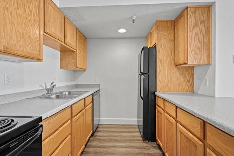 A kitchen with wooden cabinets and a black refrigerator.