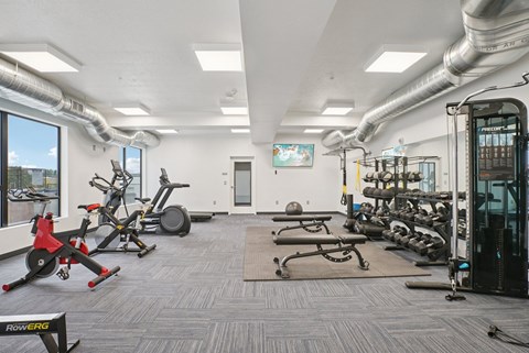 A gym with a variety of equipment including treadmills, weights, and exercise machines.
