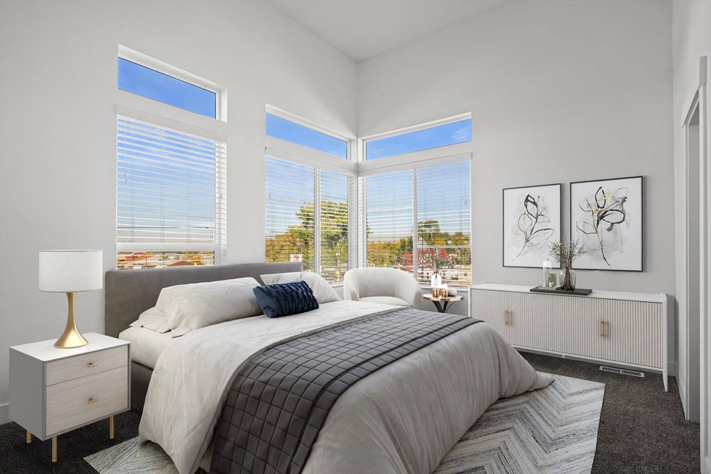 a bedroom with a large bed and three large windows