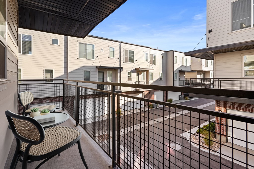 a balcony with a table and chairs and a view of apartment buildings