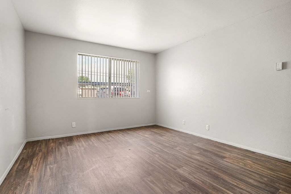 an empty living room with wood flooring and a window