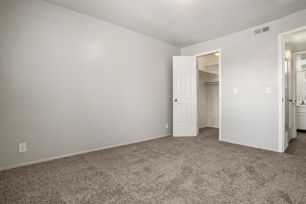 a bedroom with a carpeted floor and a door to a closet