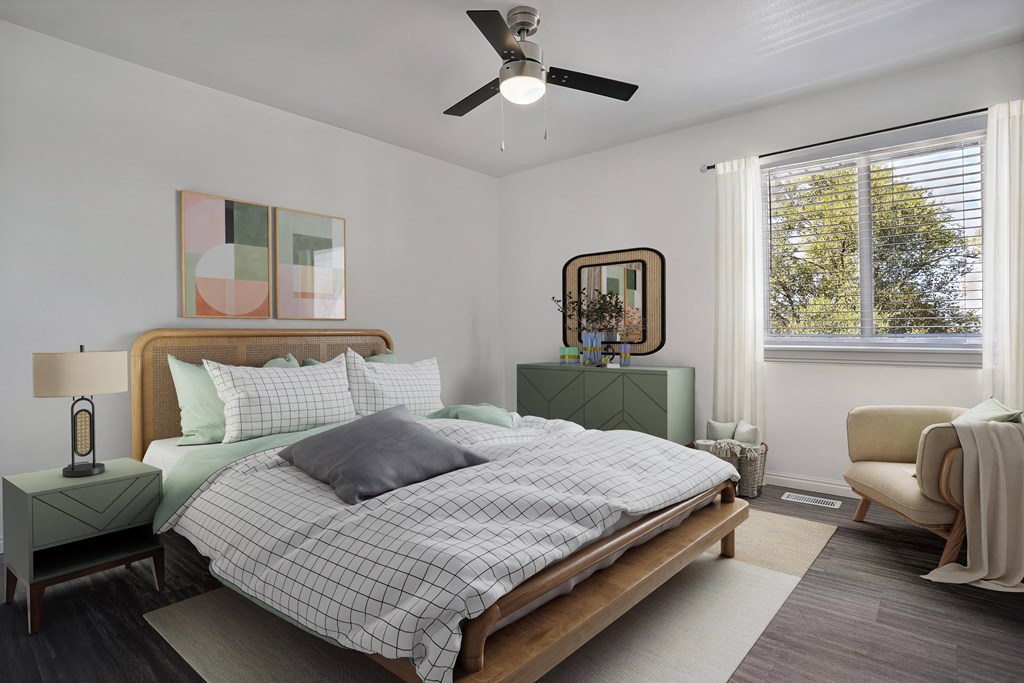 A bedroom with a bed, nightstand, chair, and a ceiling fan.