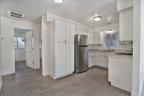 A kitchen with white cabinets and a stainless steel refrigerator.
