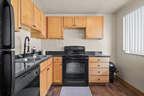 A kitchen with wooden cabinets and black appliances.
