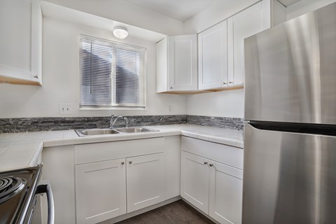 A modern kitchen with white cabinets and a stainless steel refrigerator.