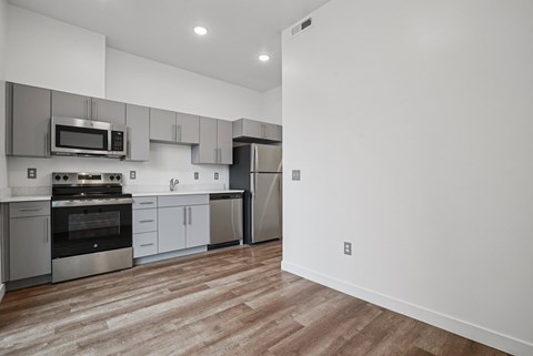 A modern kitchen with stainless steel appliances and wooden flooring.