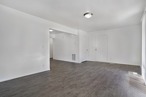 A spacious room with wooden flooring and white walls.