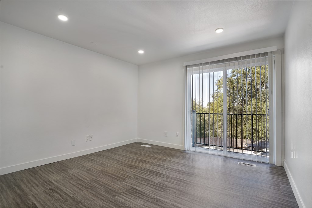 A room with a sliding glass door leading to a balcony with a black railing.