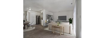 A modern living room with a white sofa, a wooden coffee table, and a TV on the wall.