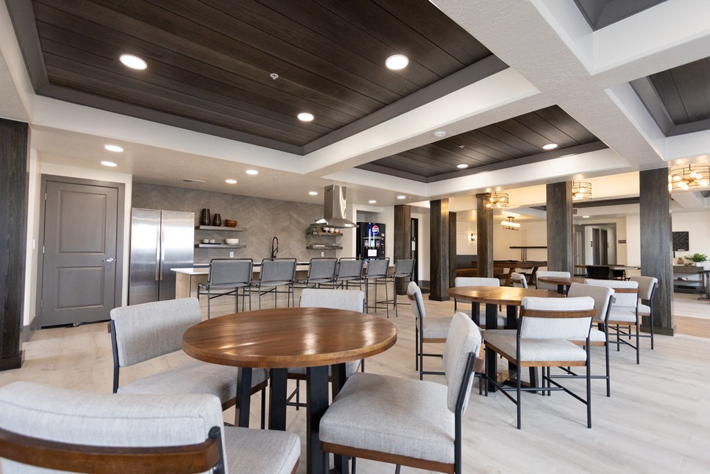 a large lobby with tables and chairs and a kitchen