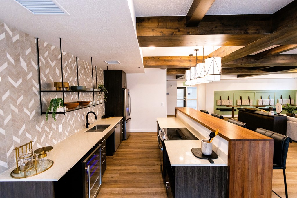 a kitchen with a long counter and a living room with a table and chairs