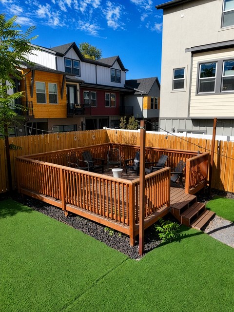 A wooden deck with a hot tub in the middle of a grassy area.