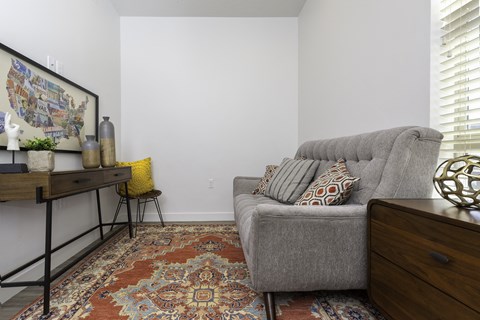 a living room with a couch and a rug and a desk