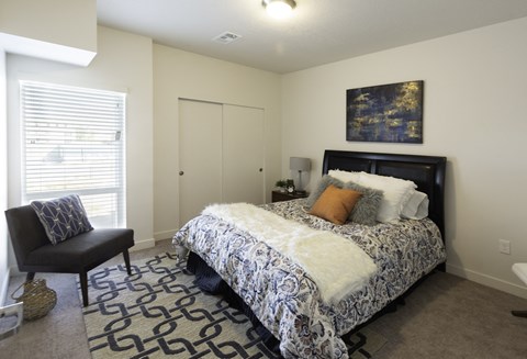 a bedroom with a bed and a chair and a window