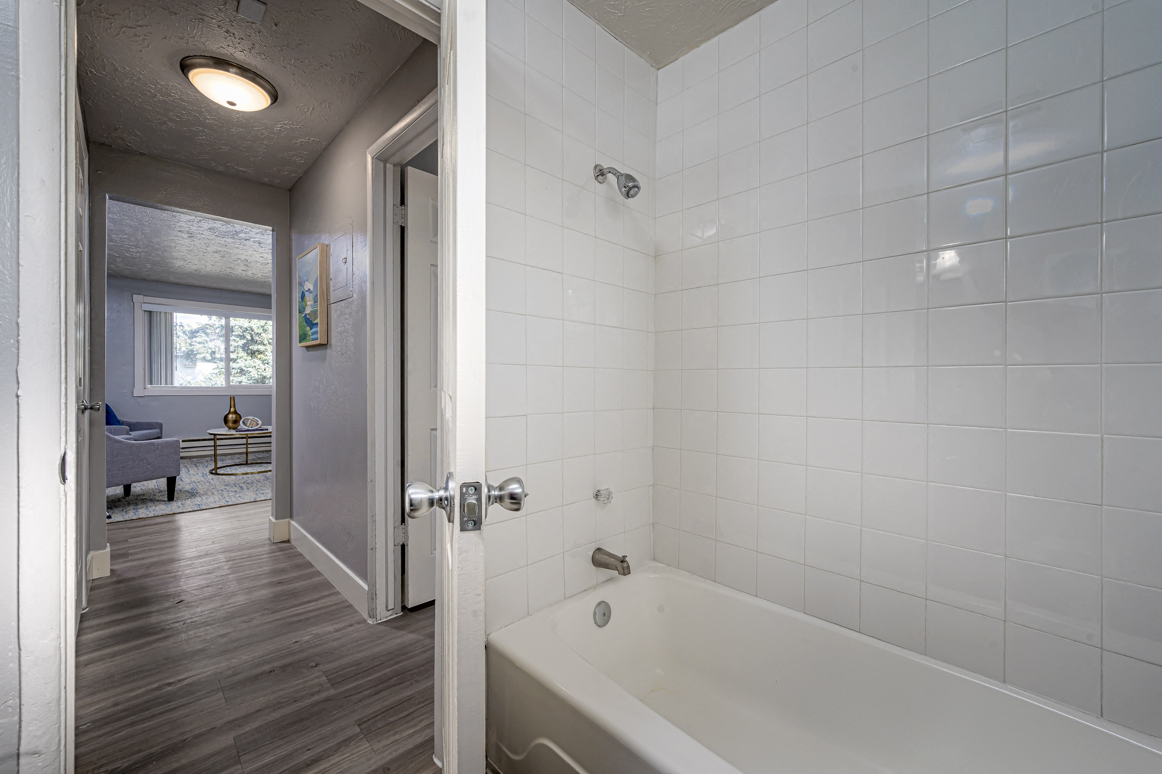 a bathroom with white tile and a white bathtub