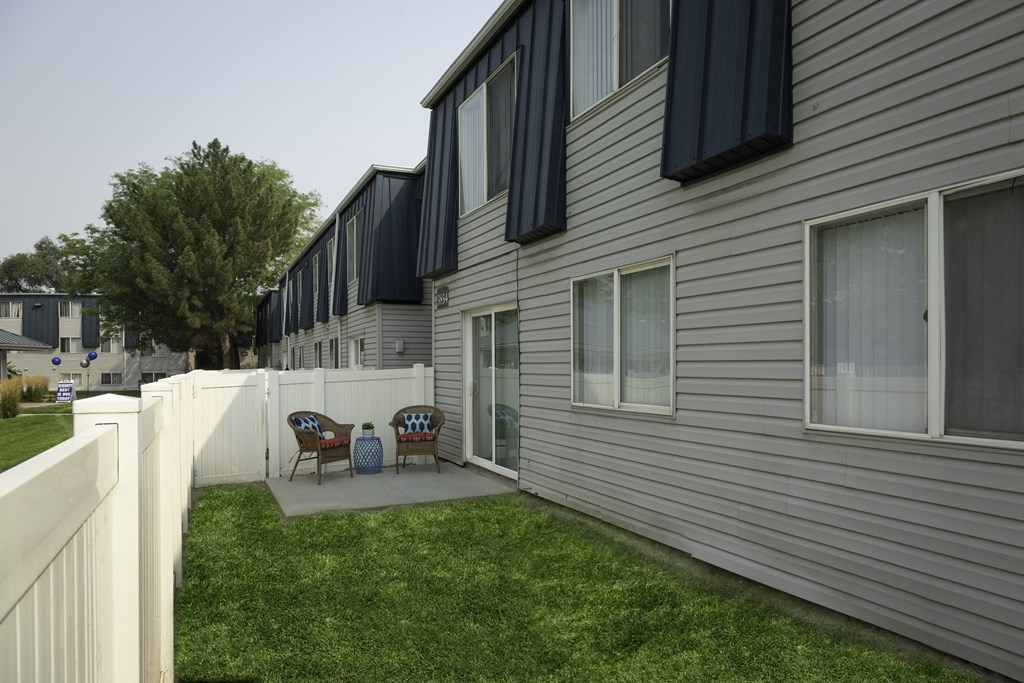 a backyard patio with chairs and a table in front of a house