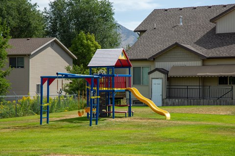 A playground with a red and blue structure and a yellow slide.