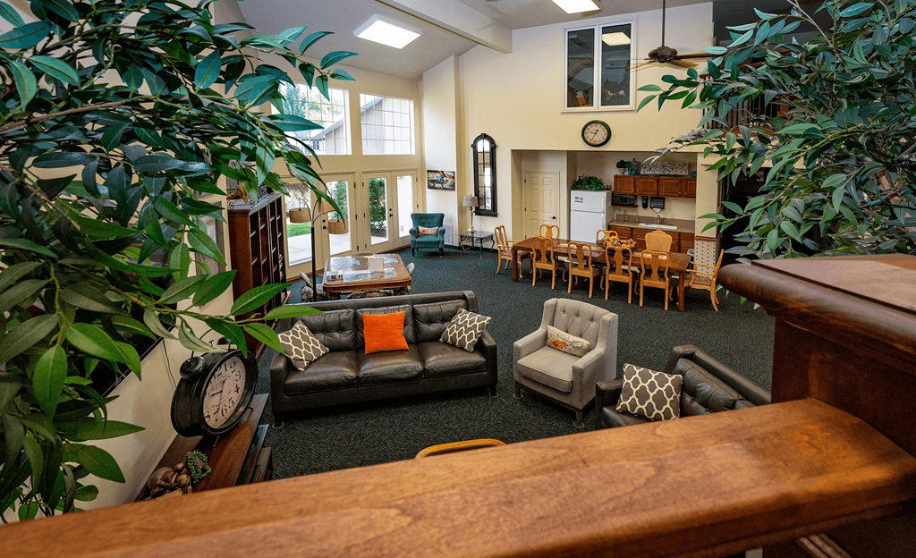 A living room with a couch, chairs, and a clock on the wall.
