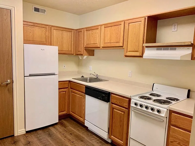 A kitchen with white appliances and wooden cabinets.