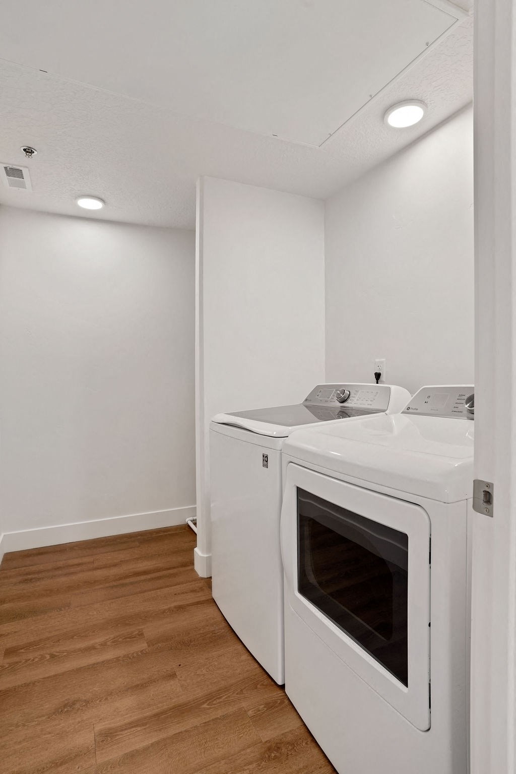 a washer and dryer in a room with a wooden floor and white walls