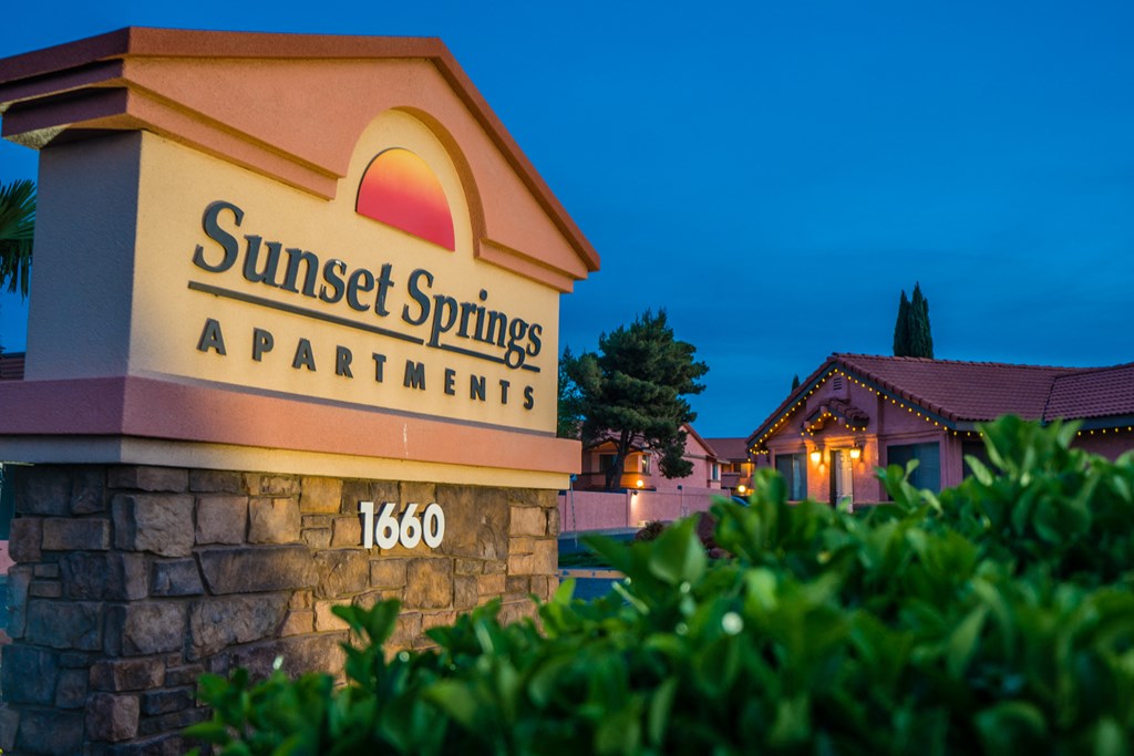 a sunset springs apartments sign on the side of a building at night