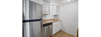 A kitchen with a stainless steel refrigerator and white cabinets.